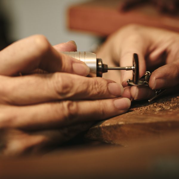 Hands of jeweler polishing a jewelry piece with flex shaft.